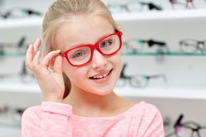 health care, people, eyesight and vision concept - little girl in glasses at optics store